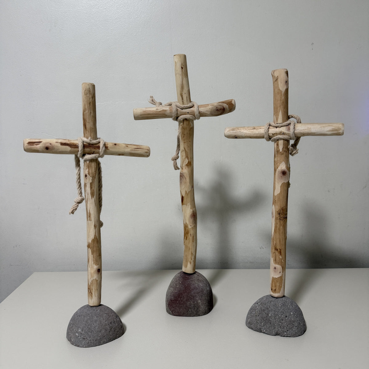 Set of three recycled wood crosses on natural rock bases, front view