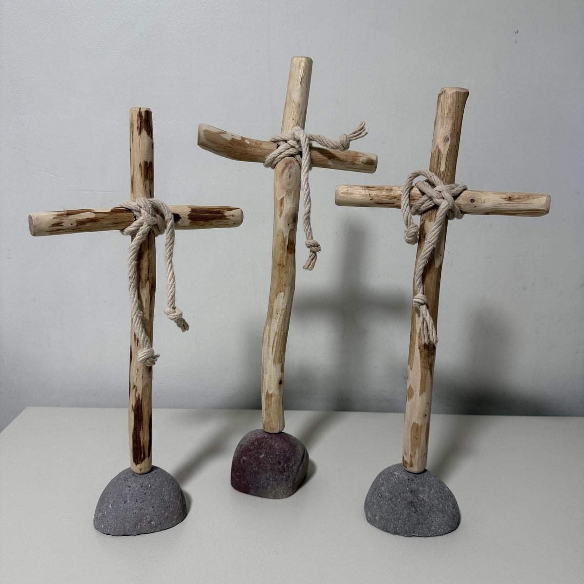 Three recycled wood crosses on rock bases, alternate front view
