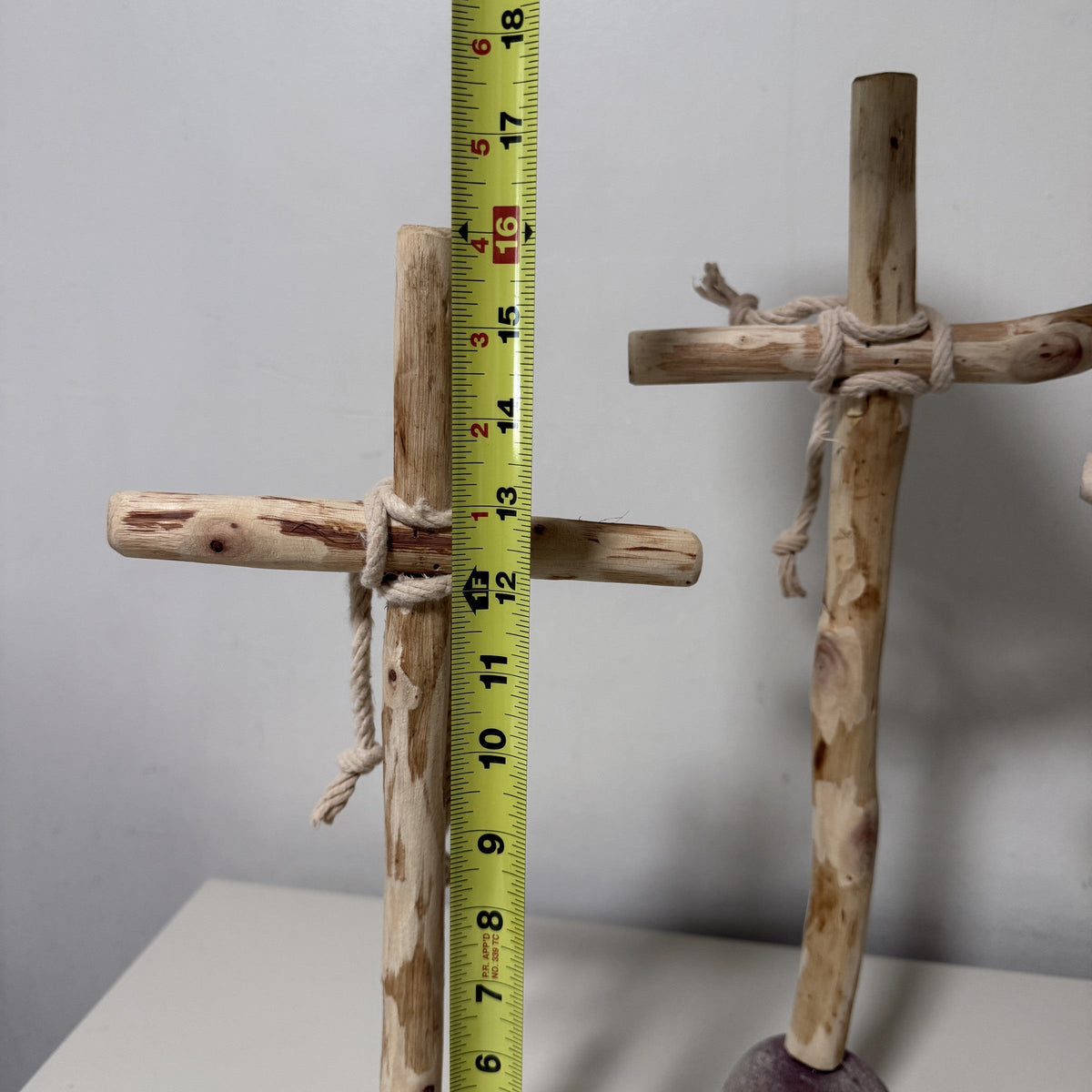 Wood cross crossarm and rope binding beside a tape measure
