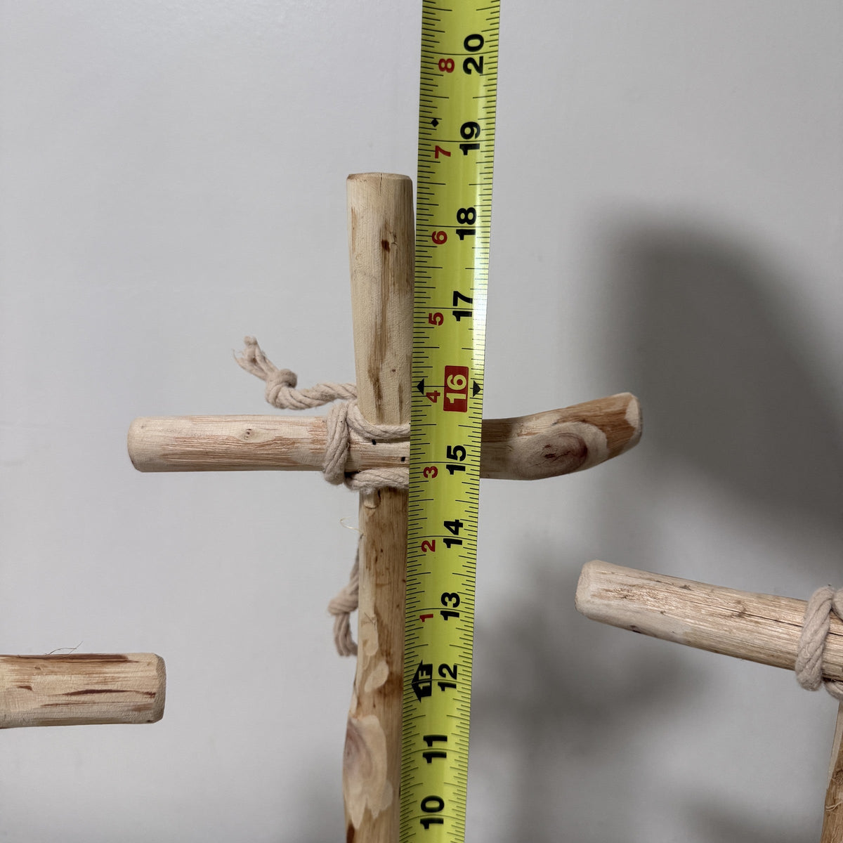 Wood cross measured against a tape measure, close view of the upright
