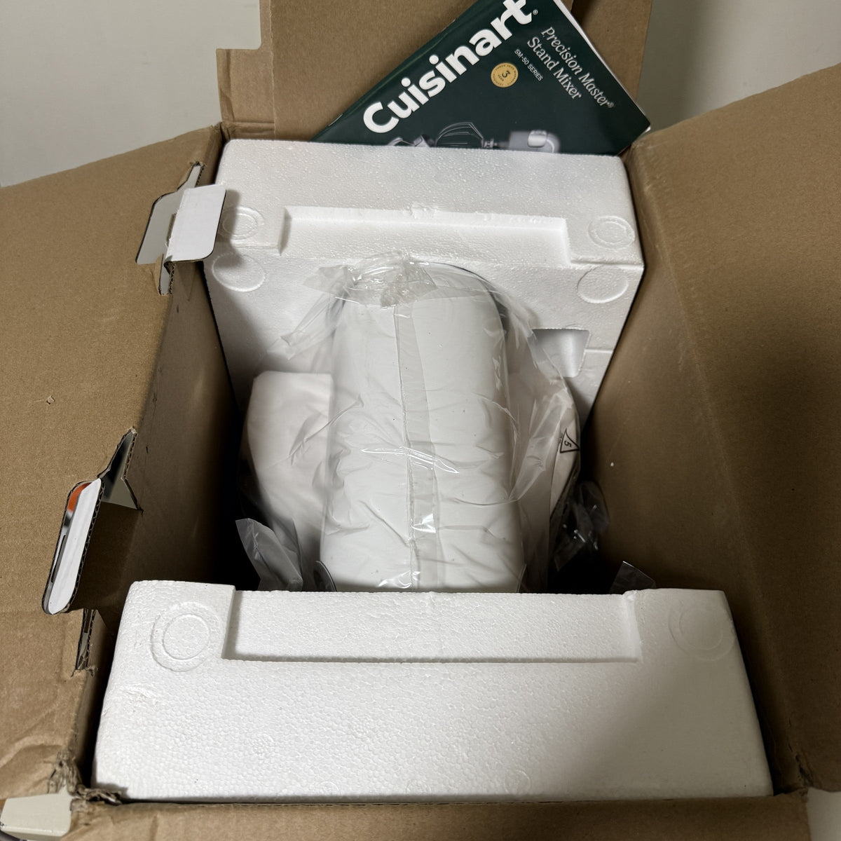 Open Cuisinart SM-50 box showing the mixer bagged in its foam packaging with the manual