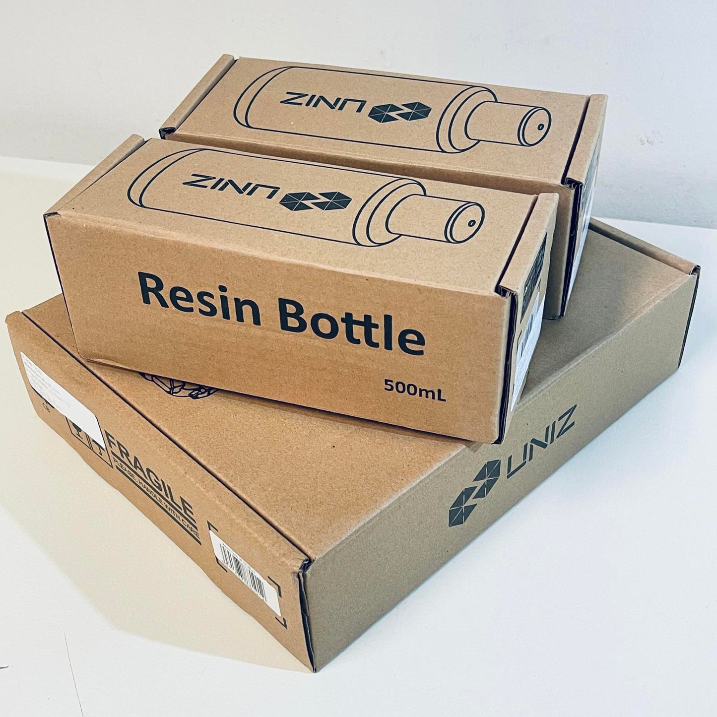 Three cardboard boxes labeled 'UNIZ' with 'Resin Bottle' and '500mL' text on a white background.